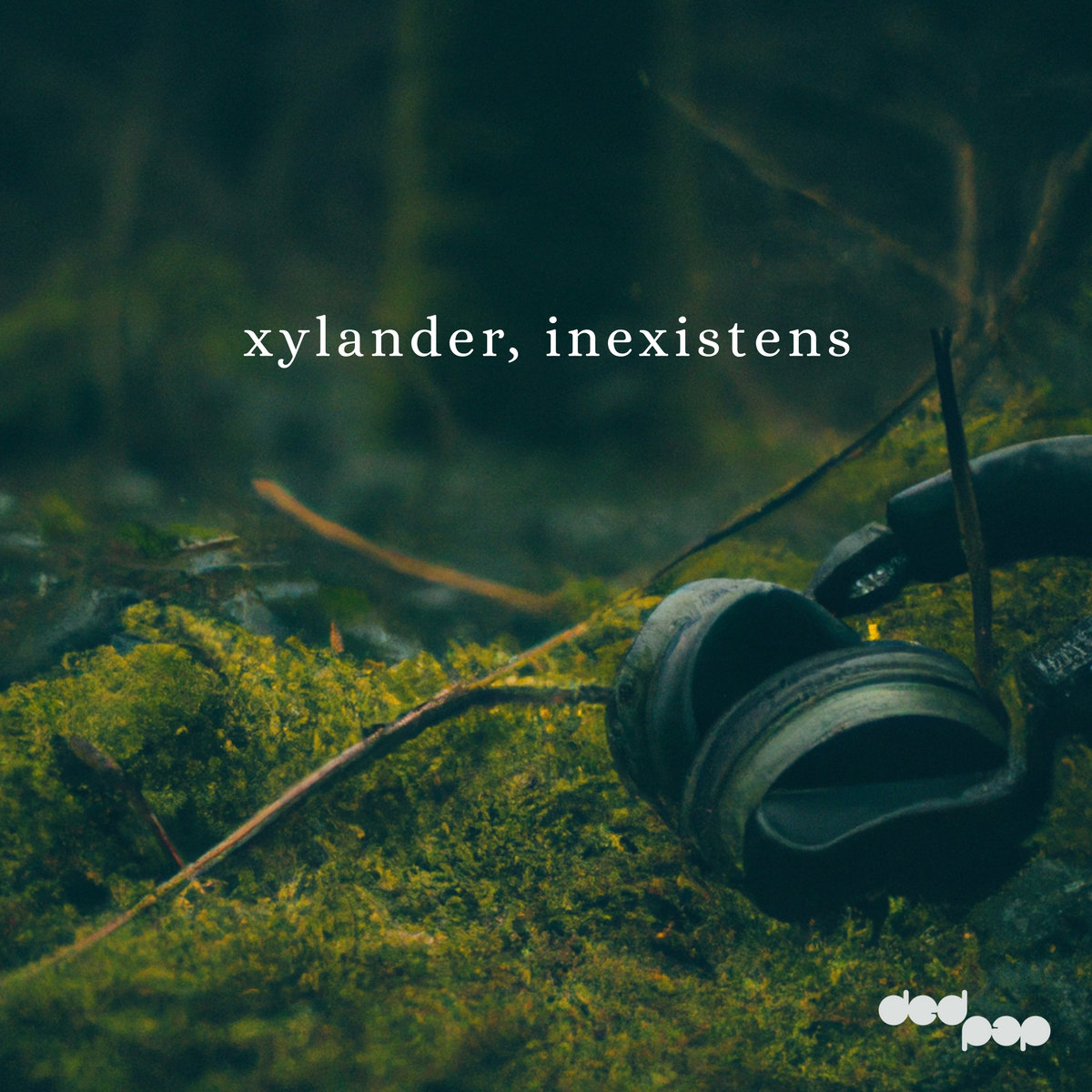 Cover art: A pair of headphones abandoned in a mossy woodland